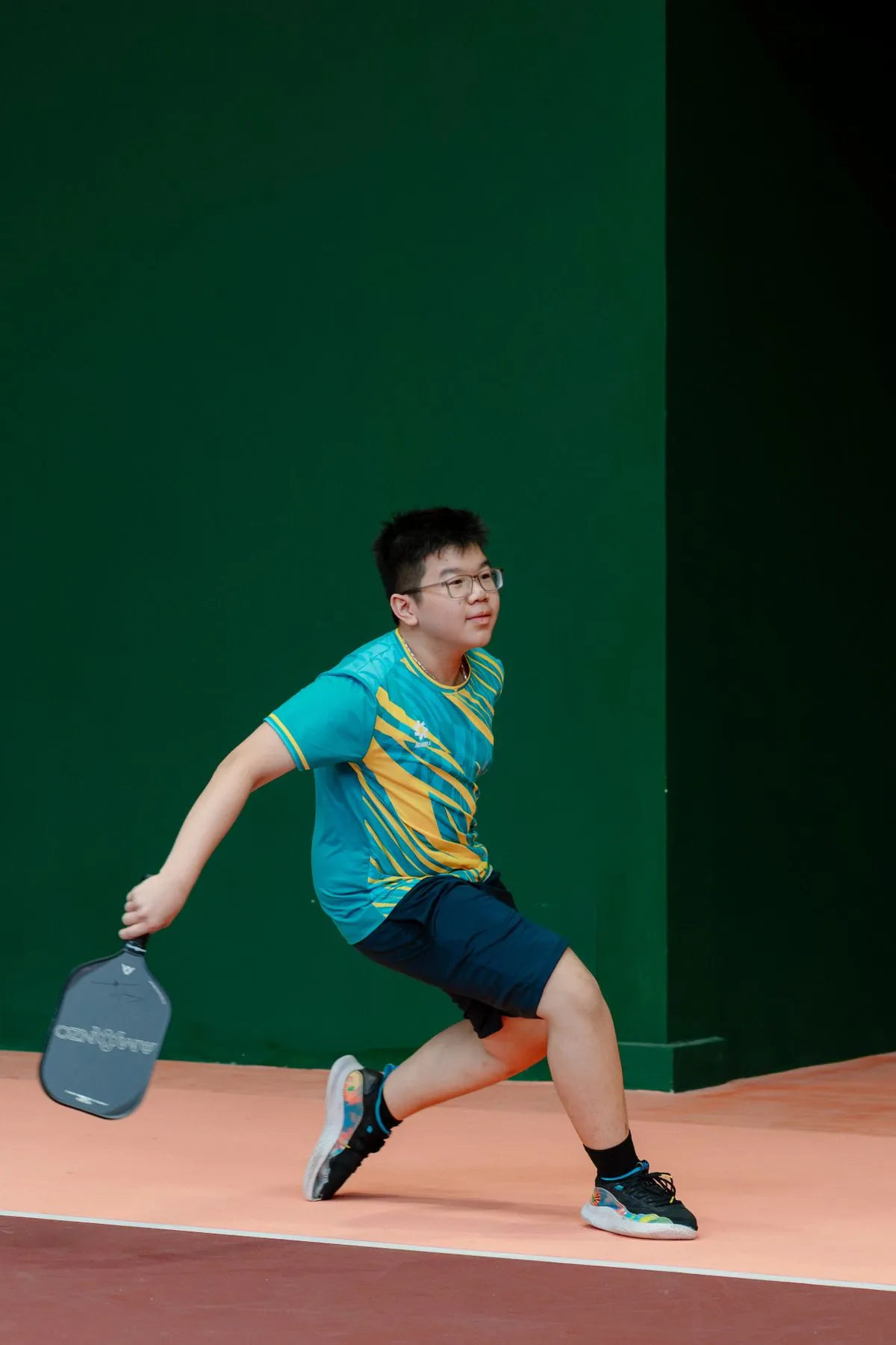 Young player reaching for a shot during a pickleball game